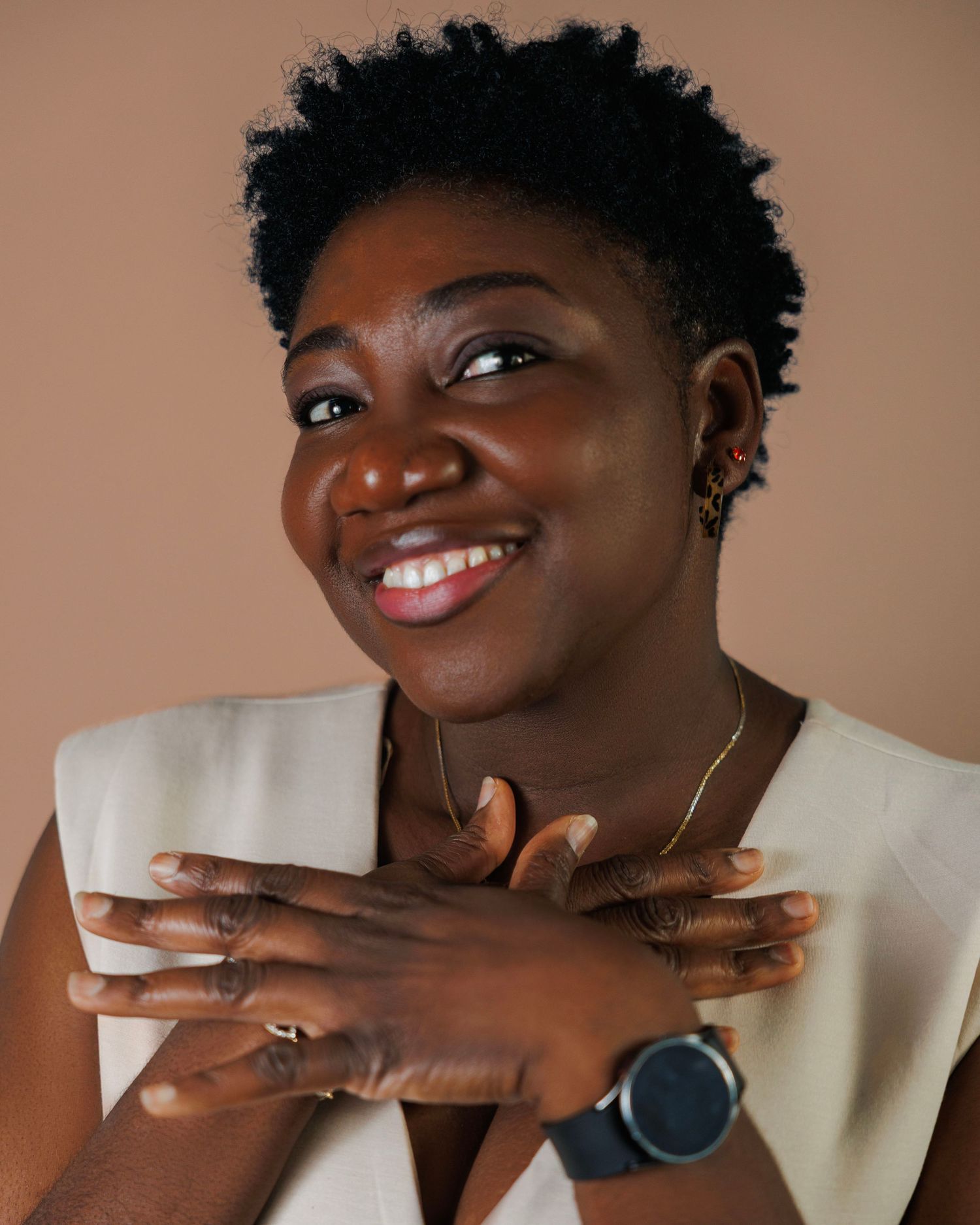 Expressive poses and smiles against a brown backdrop wearing a white top.