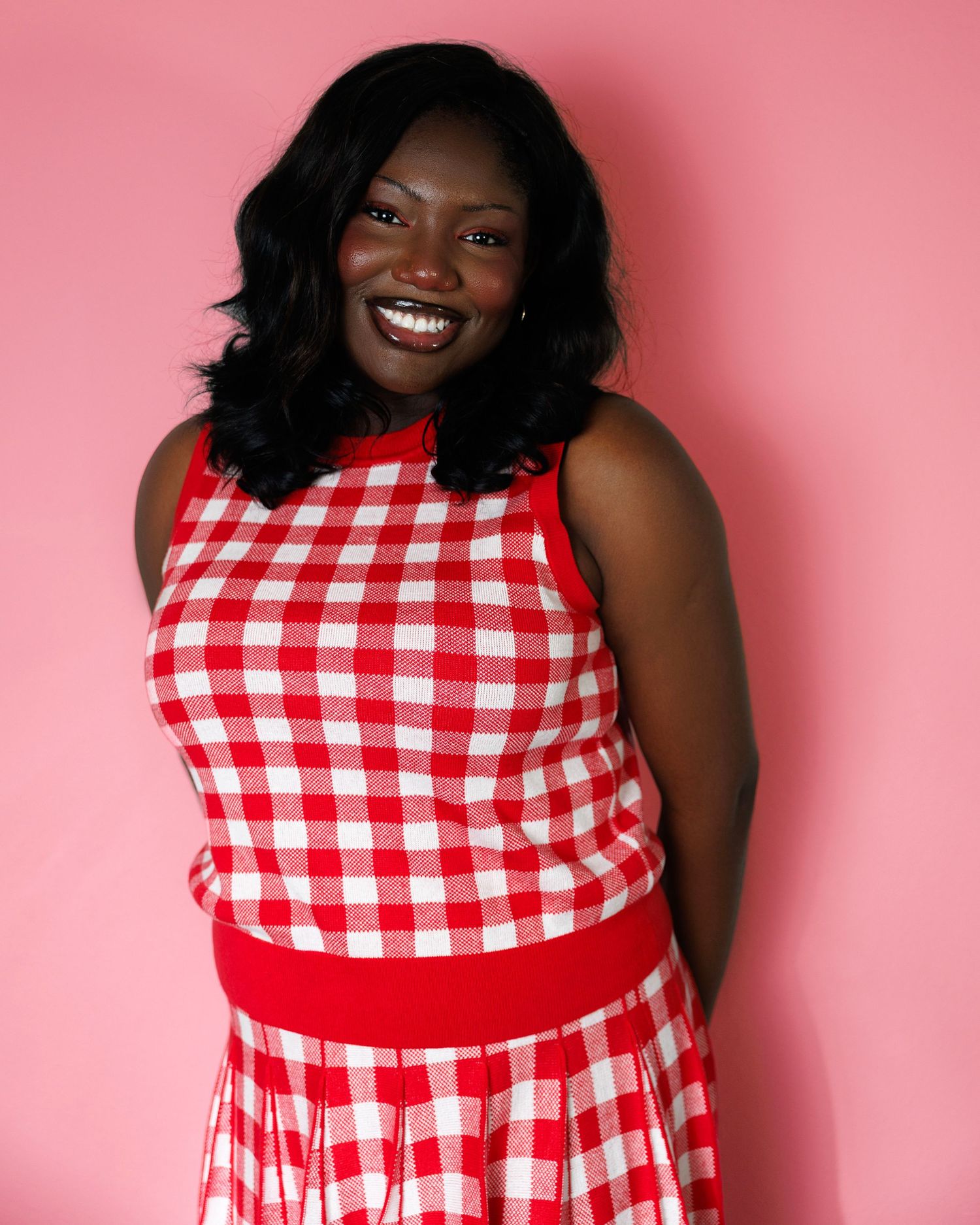 Red and white gingham dress against pink background in fashion photography series.