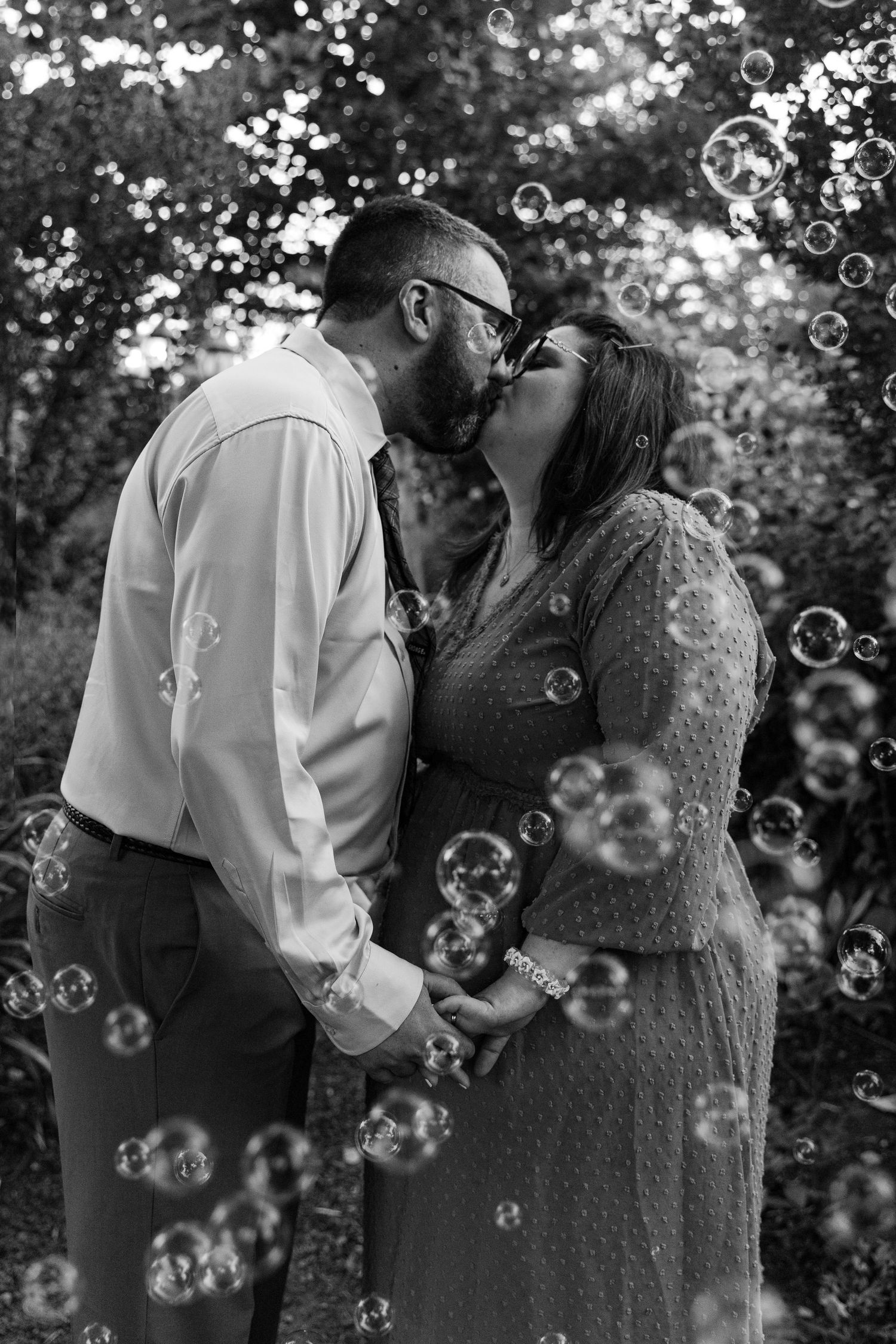Garden wedding in Oregon. Couple in wedding attire kisses during bubble send-off.