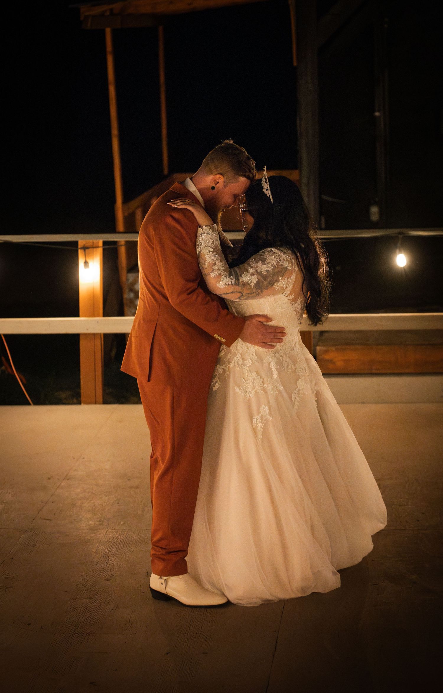 A romantic dance sequence of a couple in wedding attire silhouetted against warm lighting on an outdoor deck at night.