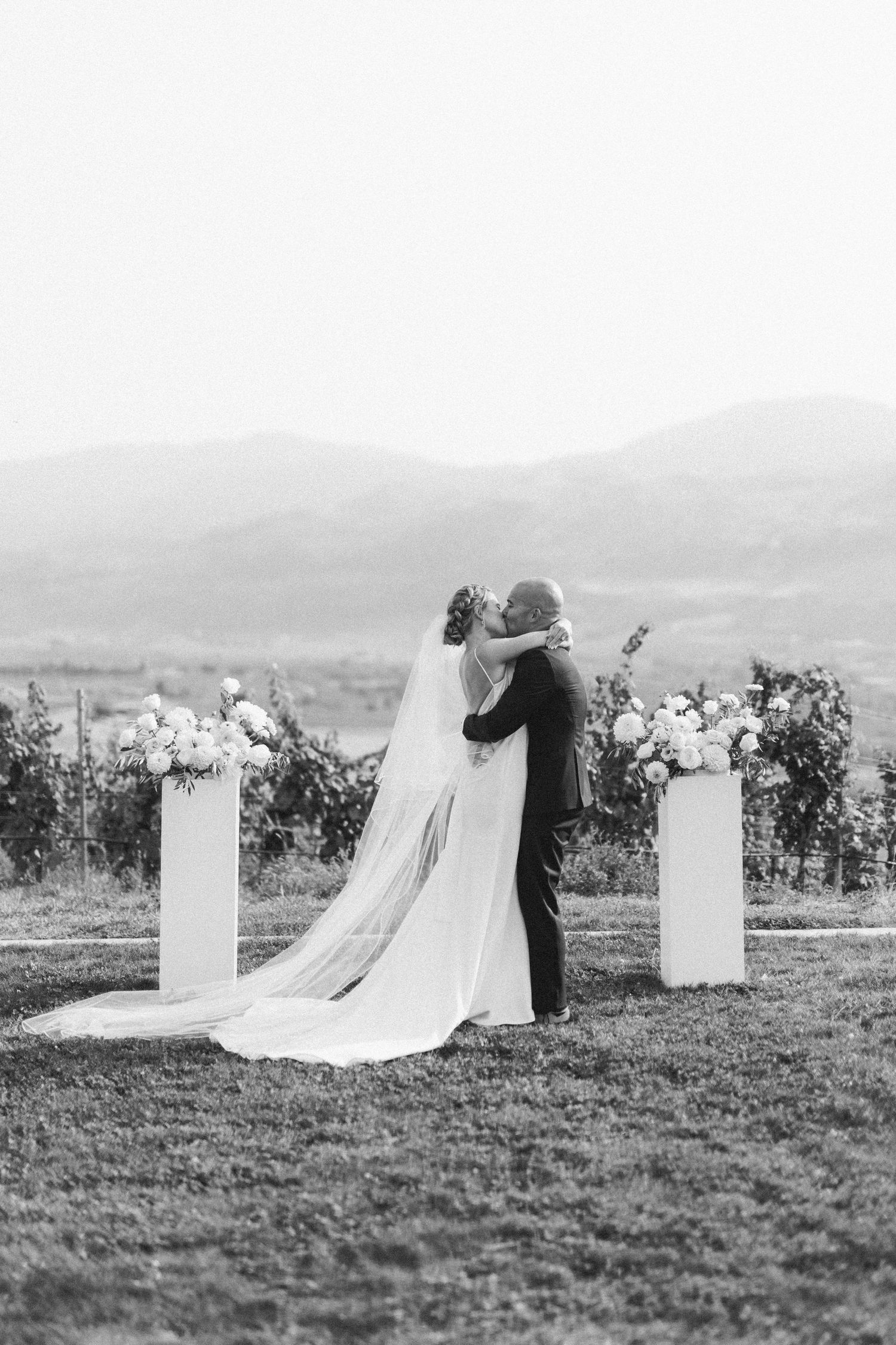 Black and white photo of a bride and groom sharing an intimate moment in a vineyard setting.