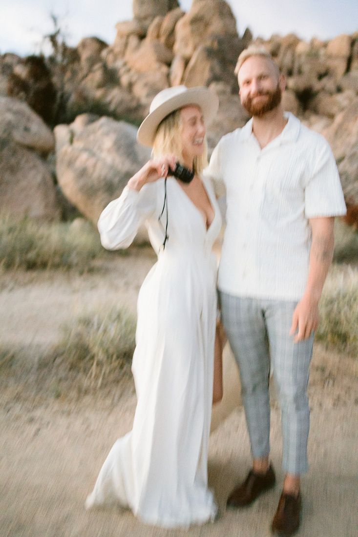A romantic desert photoshoot featuring a flowing white dress and casual menswear.