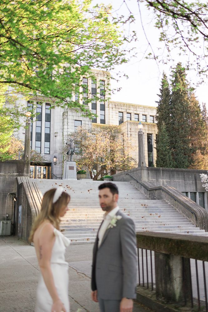 Couple poses in front of grand stone staircase at historic building.
