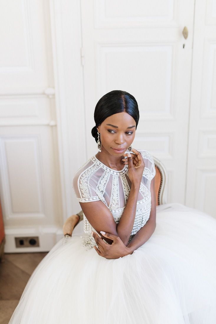Portrait of a bride wearing a tea-length wedding dress with beaded cap sleeves and tulle skirt.