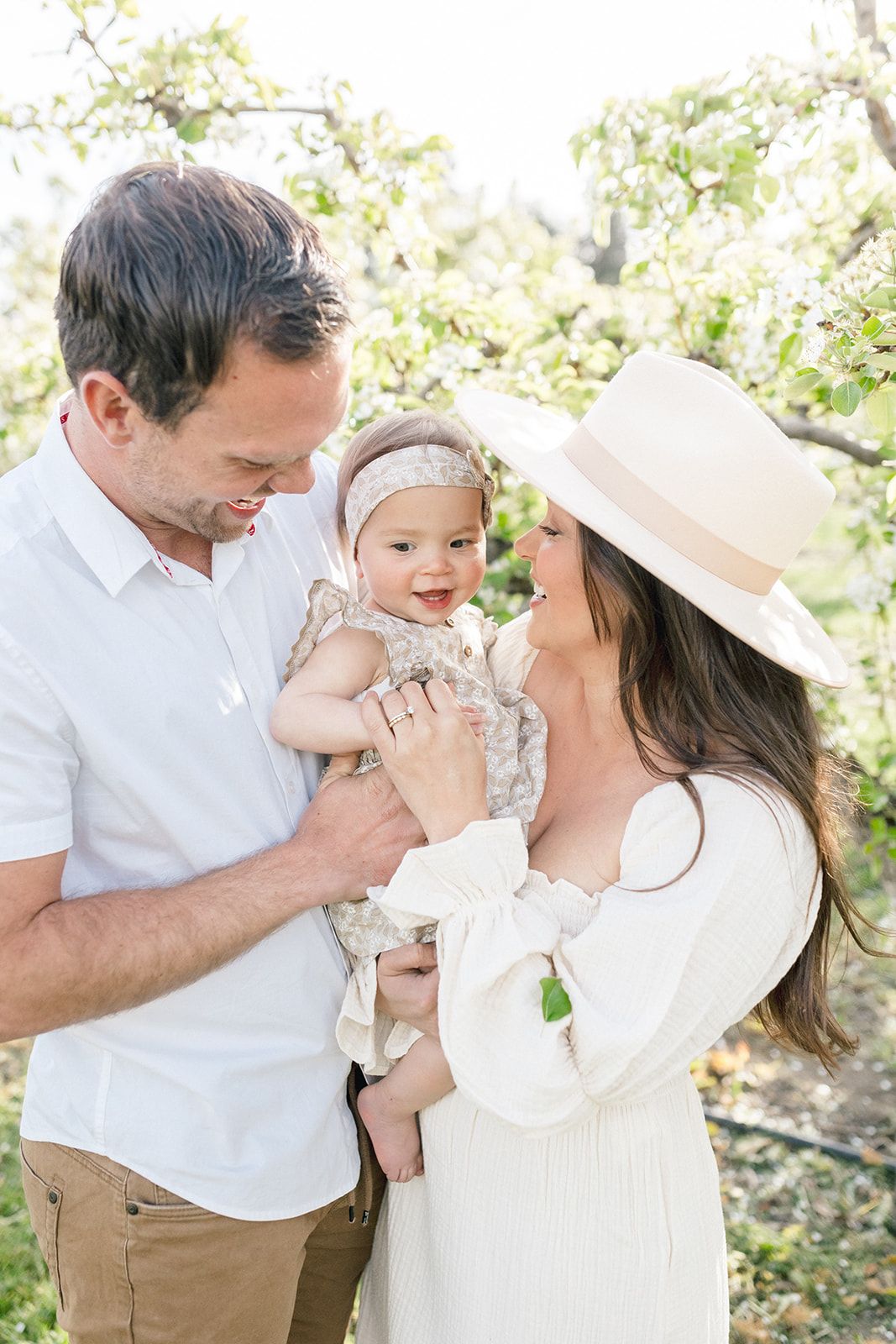 A family shares a tender moment together outdoors among blooming trees on a bright sunny day.