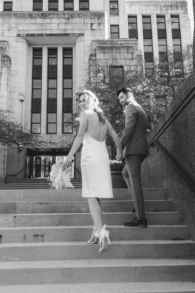 Classic black and white wedding photo on historic building steps with architectural details.