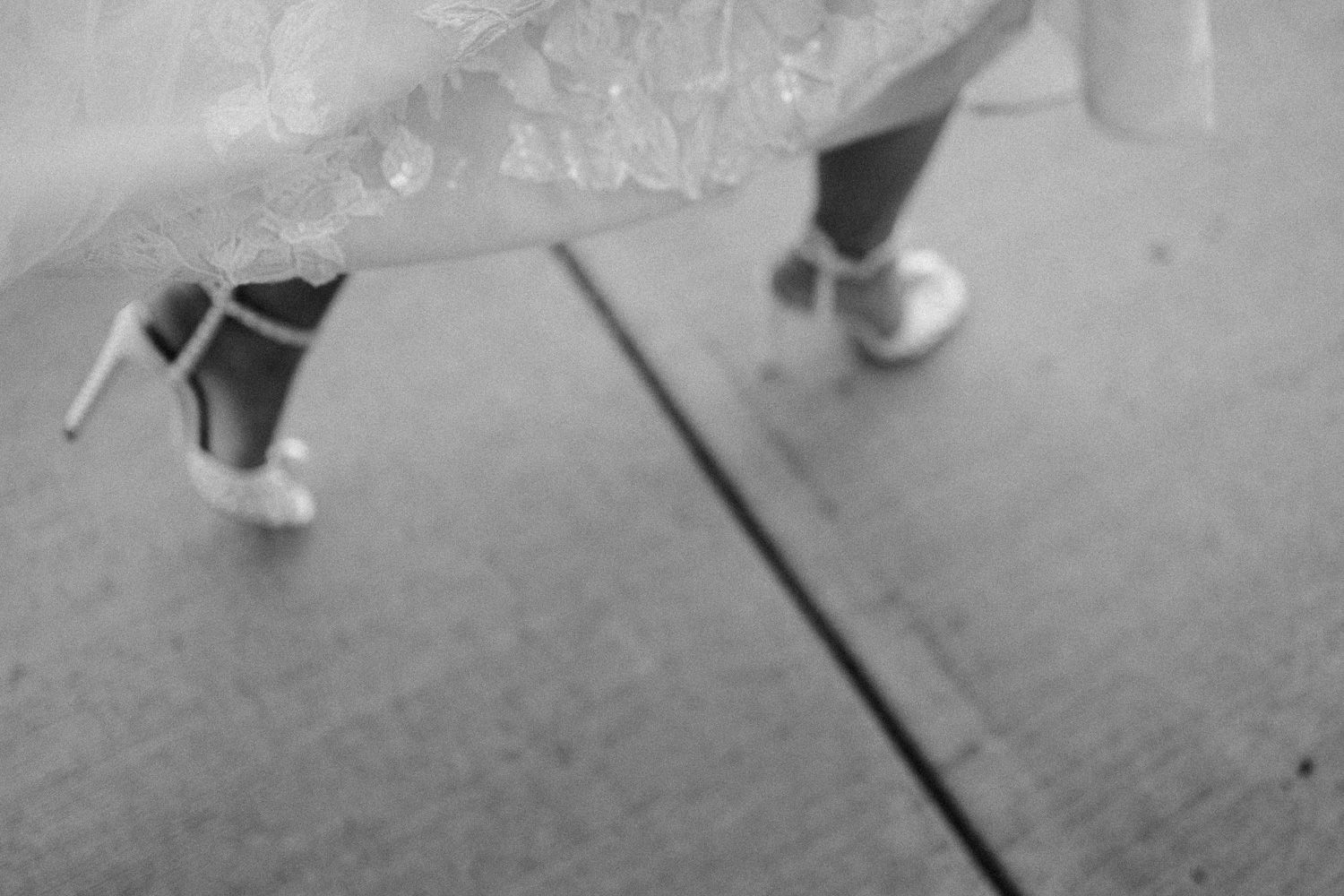 Black and white detail shot of bridal shoes and dress hem.