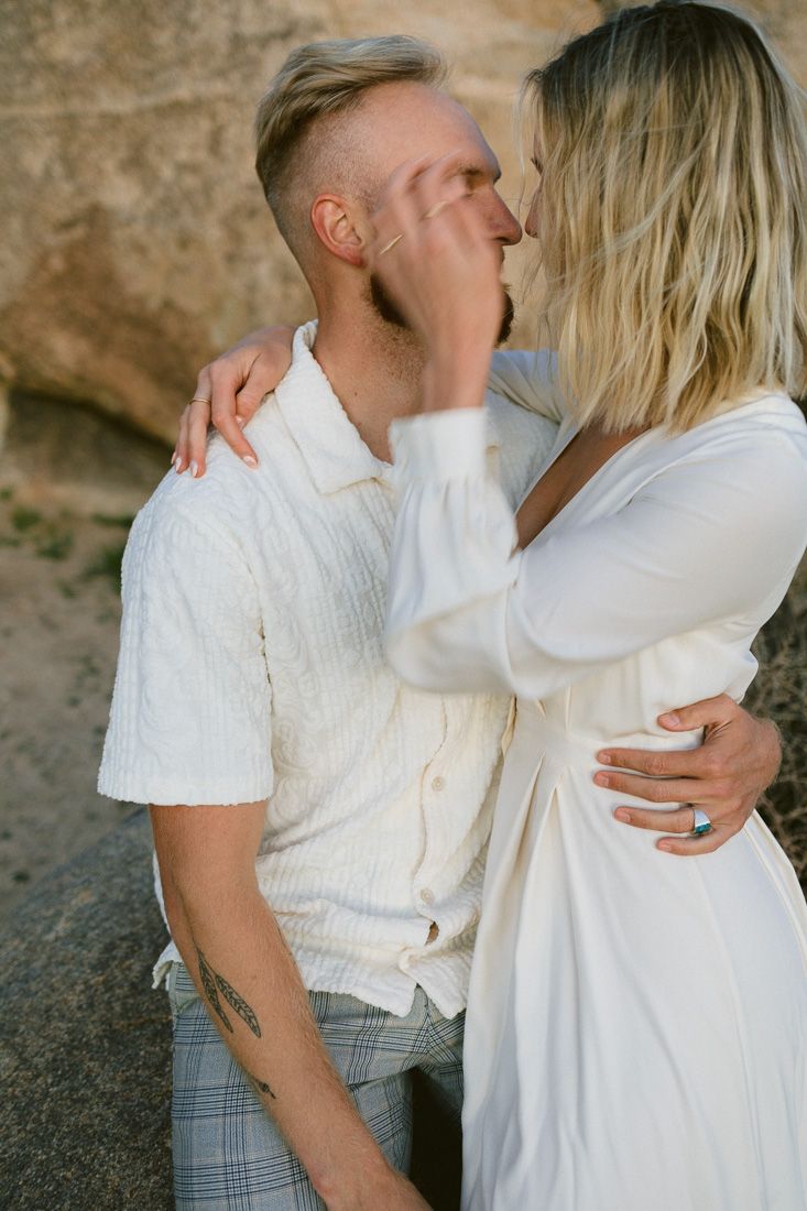 An intimate moment shared between two people against a rocky desert backdrop.