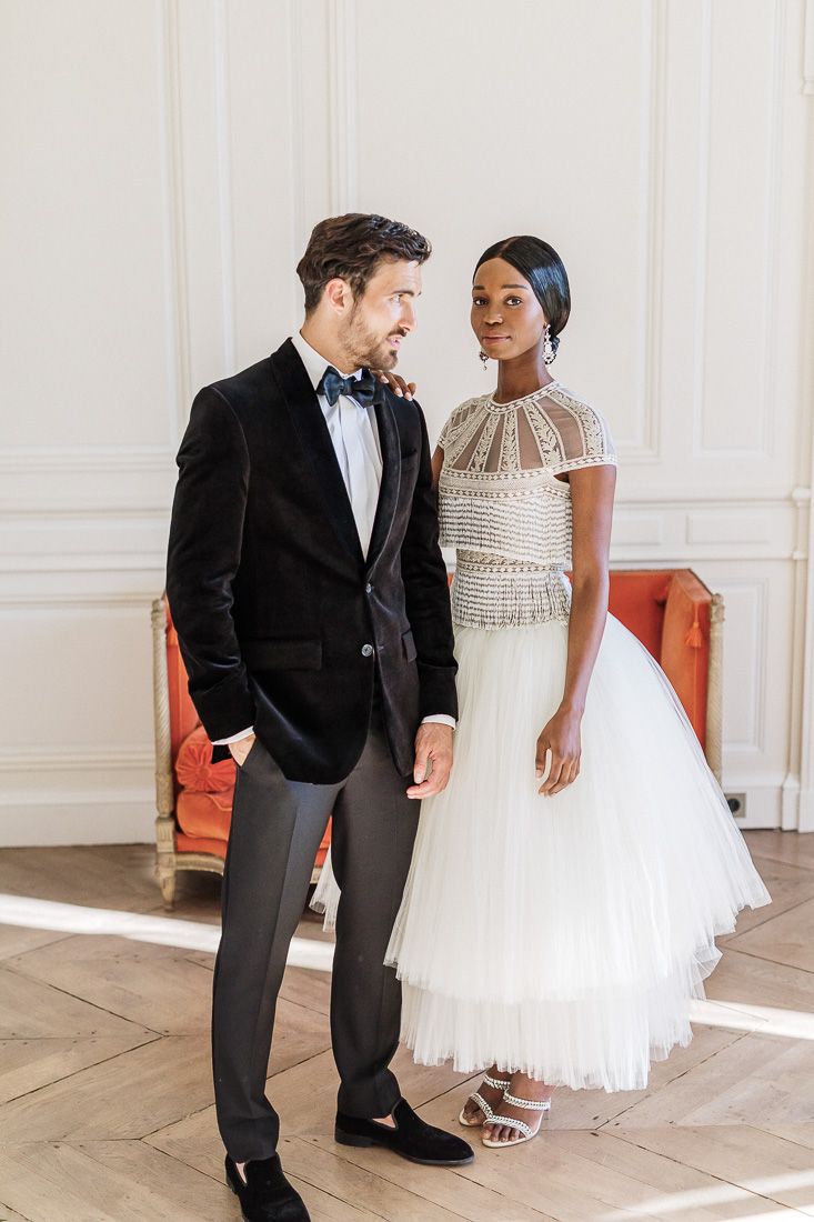 Elegant couple in wedding attire posing together on herringbone floors.