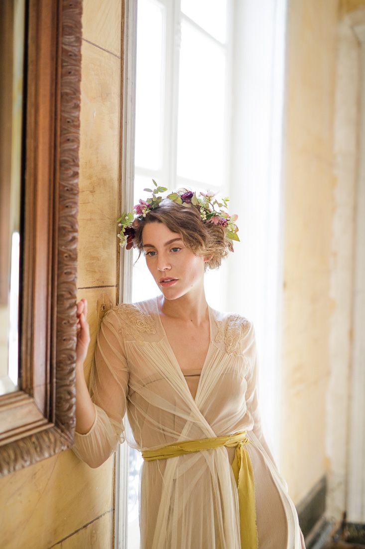 Romantic portrait by a window featuring a cream dress with yellow sash and floral headpiece.