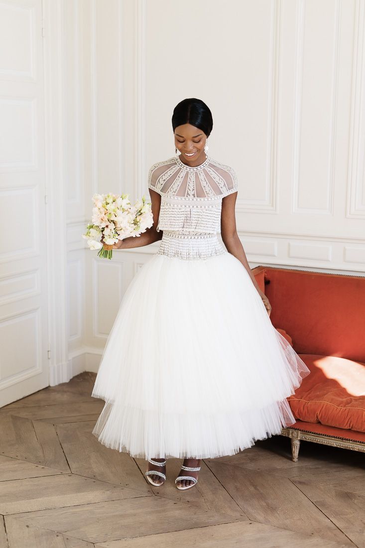 Tea-length wedding dress with tulle skirt and high neck detail photographed by orange sofa.