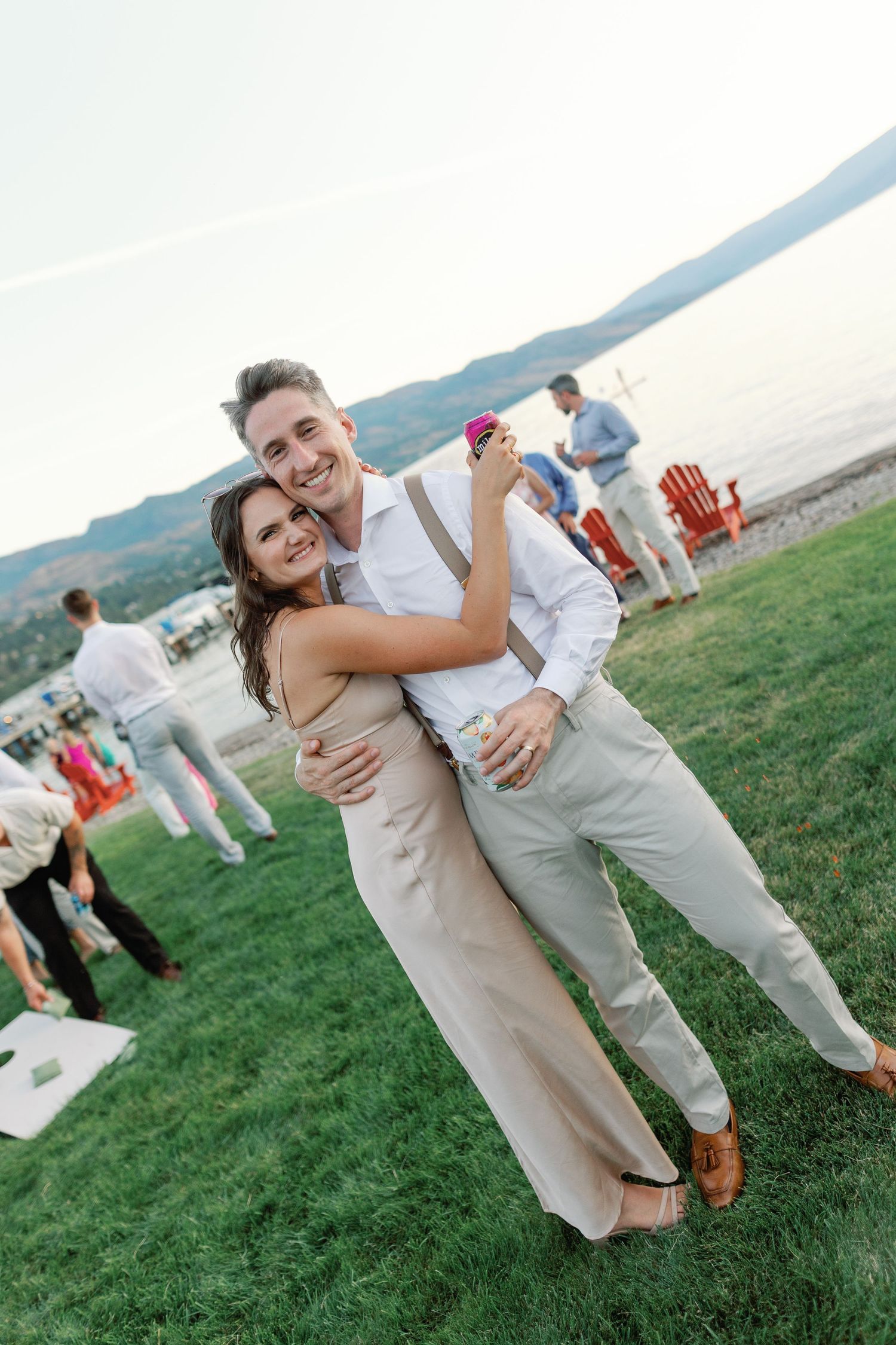 A couple dances joyfully on a grassy lawn at an outdoor wedding reception with guests in the background.