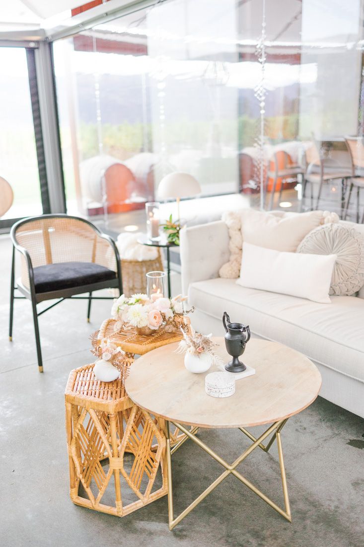Modern lounge area with white sofa, round coffee table and rattan accents in a light-filled space.