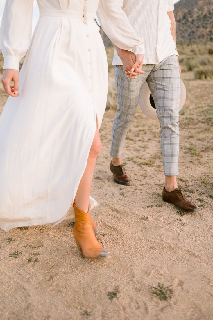Detail shot of contrasting outfits and footwear while walking on desert path.