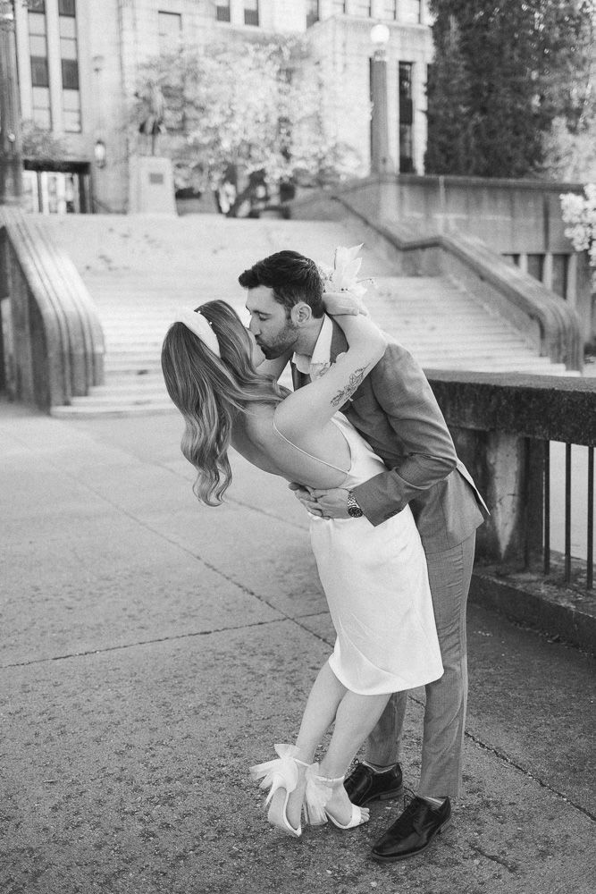 Black and white photo of romantic dip pose in front of stone steps.