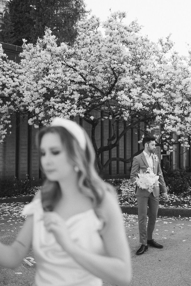 A black and white wedding photo with cherry blossoms and a couple in formal attire.