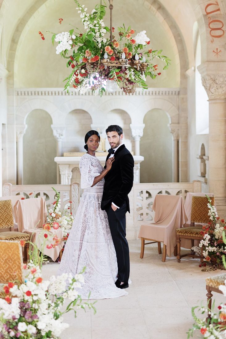 Wedding ceremony venue with ornate arches, hanging floral installation and vintage seating.