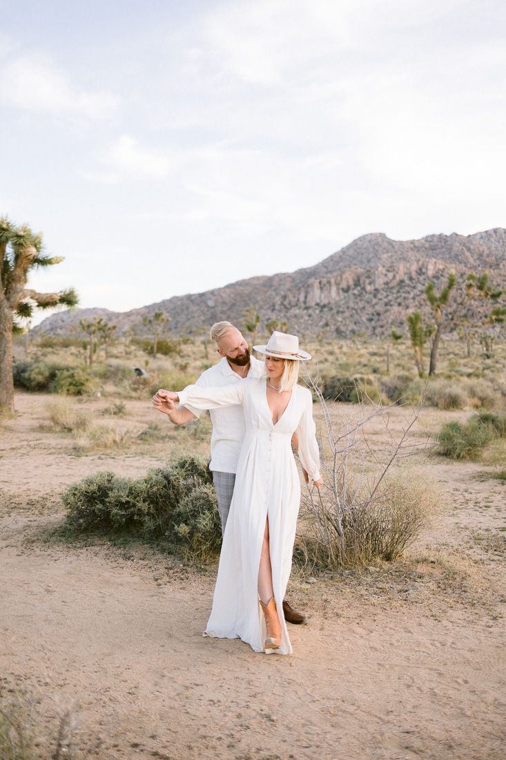 Dreamy desert photography featuring white flowing dress and casual style against mountain backdrop.