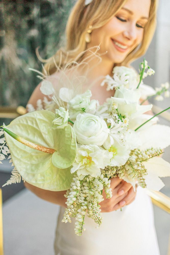 A delicate white and green bridal bouquet featuring ranunculus, anthurium and ferns.