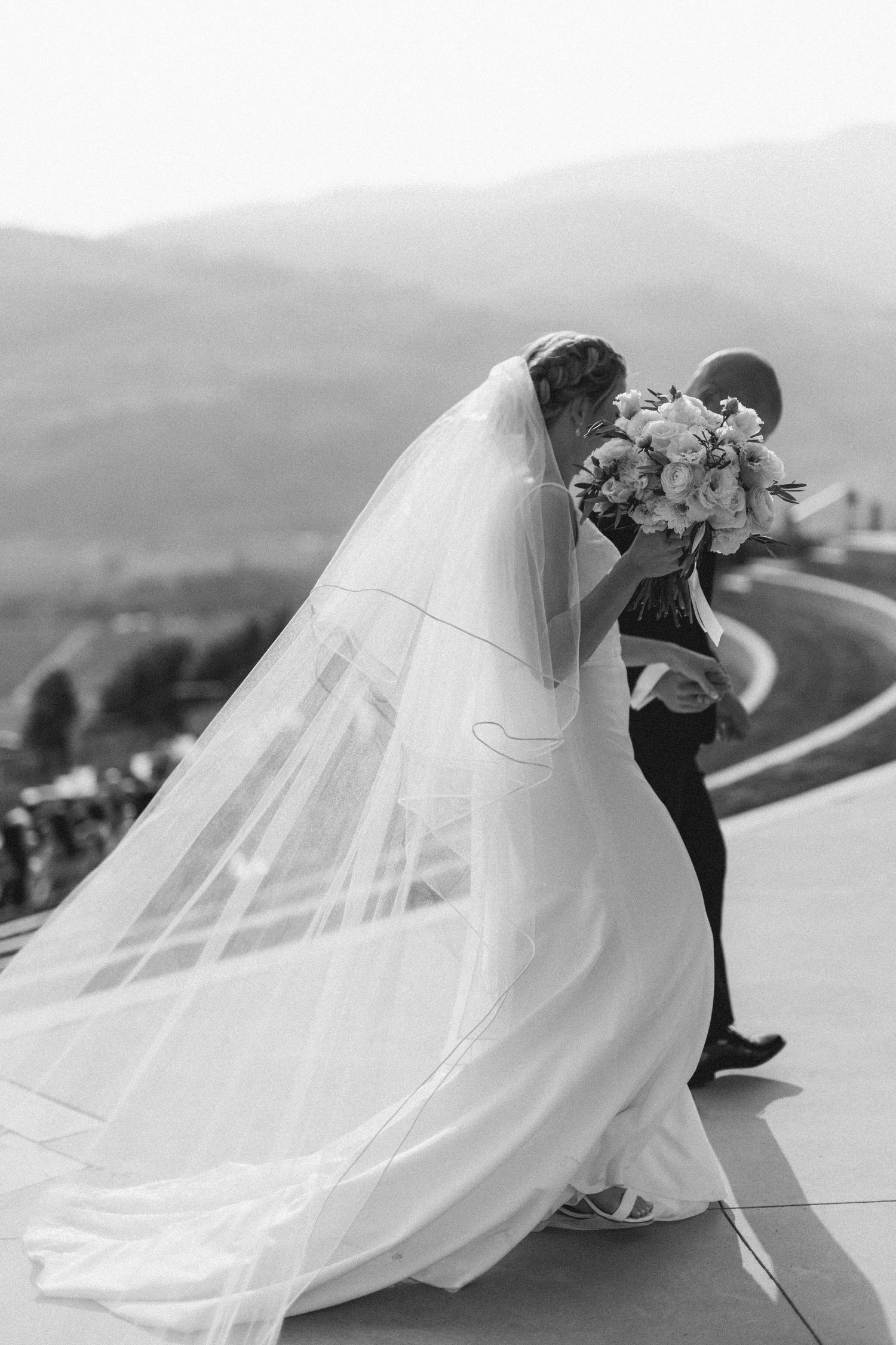 A series of romantic black and white wedding photos showing a couple with a flowing veil against a mountain landscape.