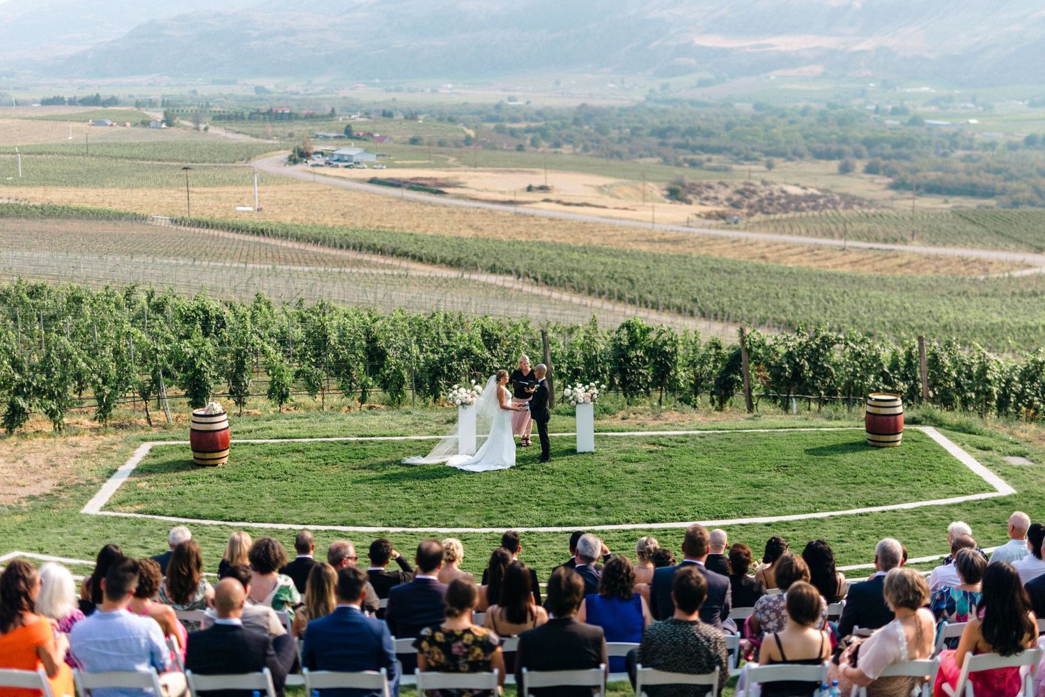 Wedding ceremony overlooking a vast valley with rows of guests seated outdoors.