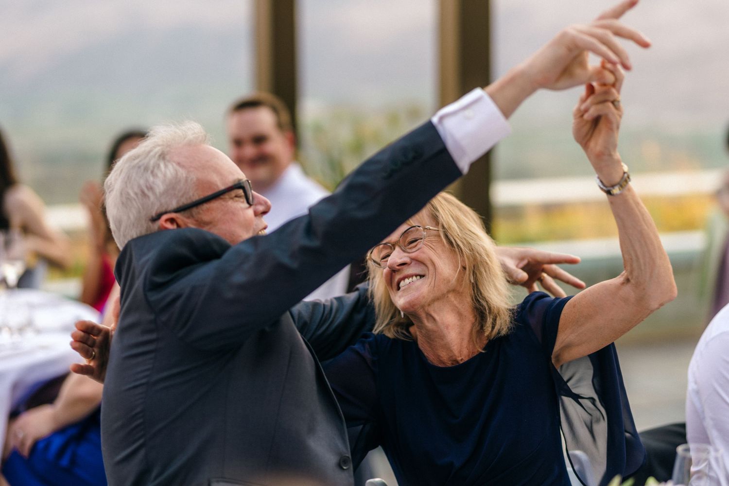 Wedding guests celebrating with arms raised during outdoor reception.