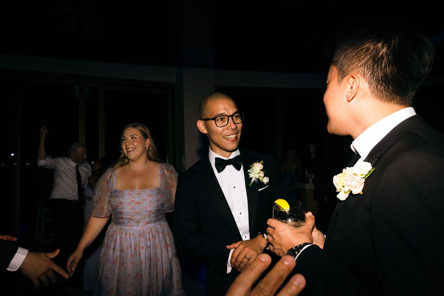 Wedding guests enjoying themselves on a dimly lit dance floor at the reception.