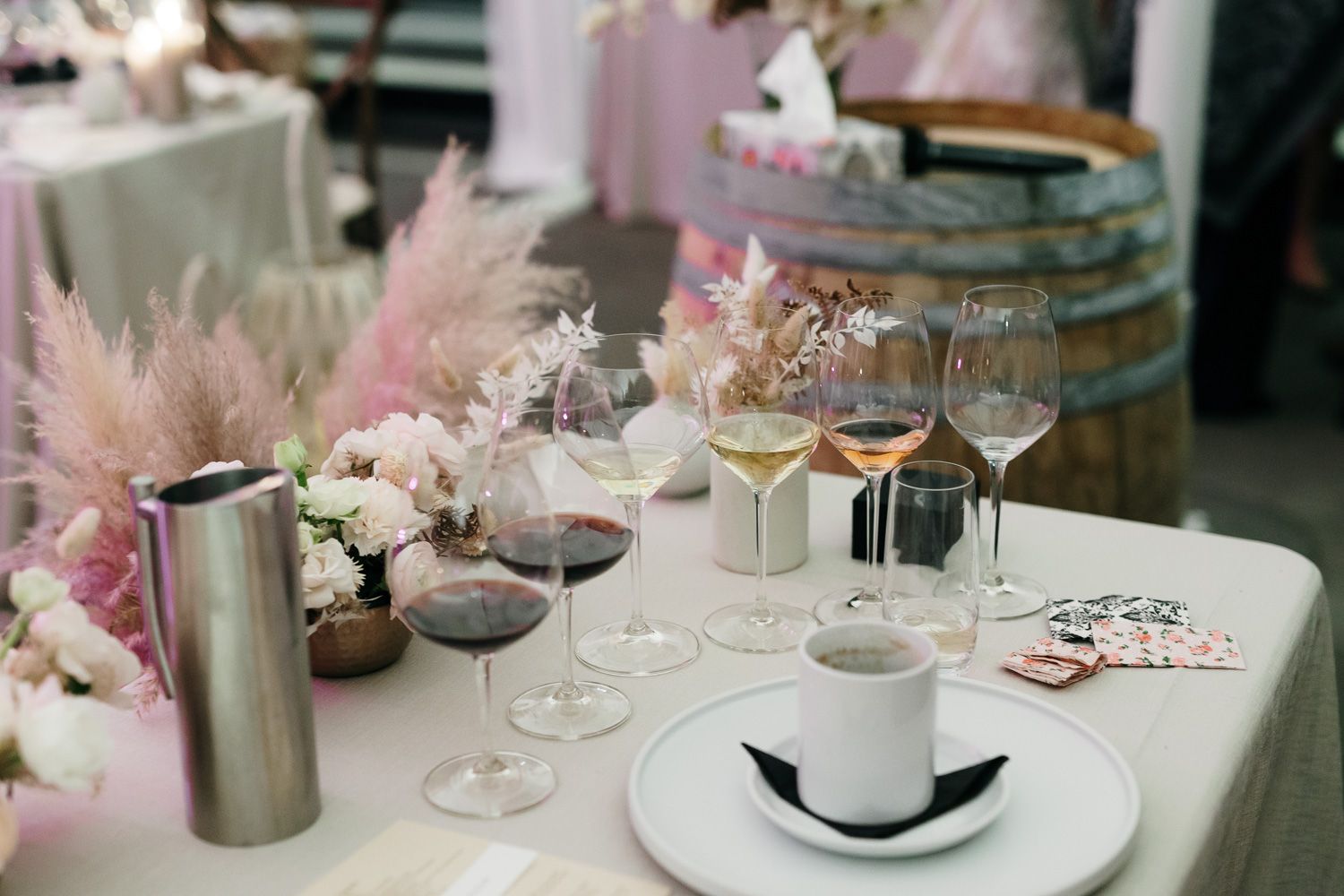 Elegant table setting with wine glasses, floral arrangements and pampas grass at wedding reception.