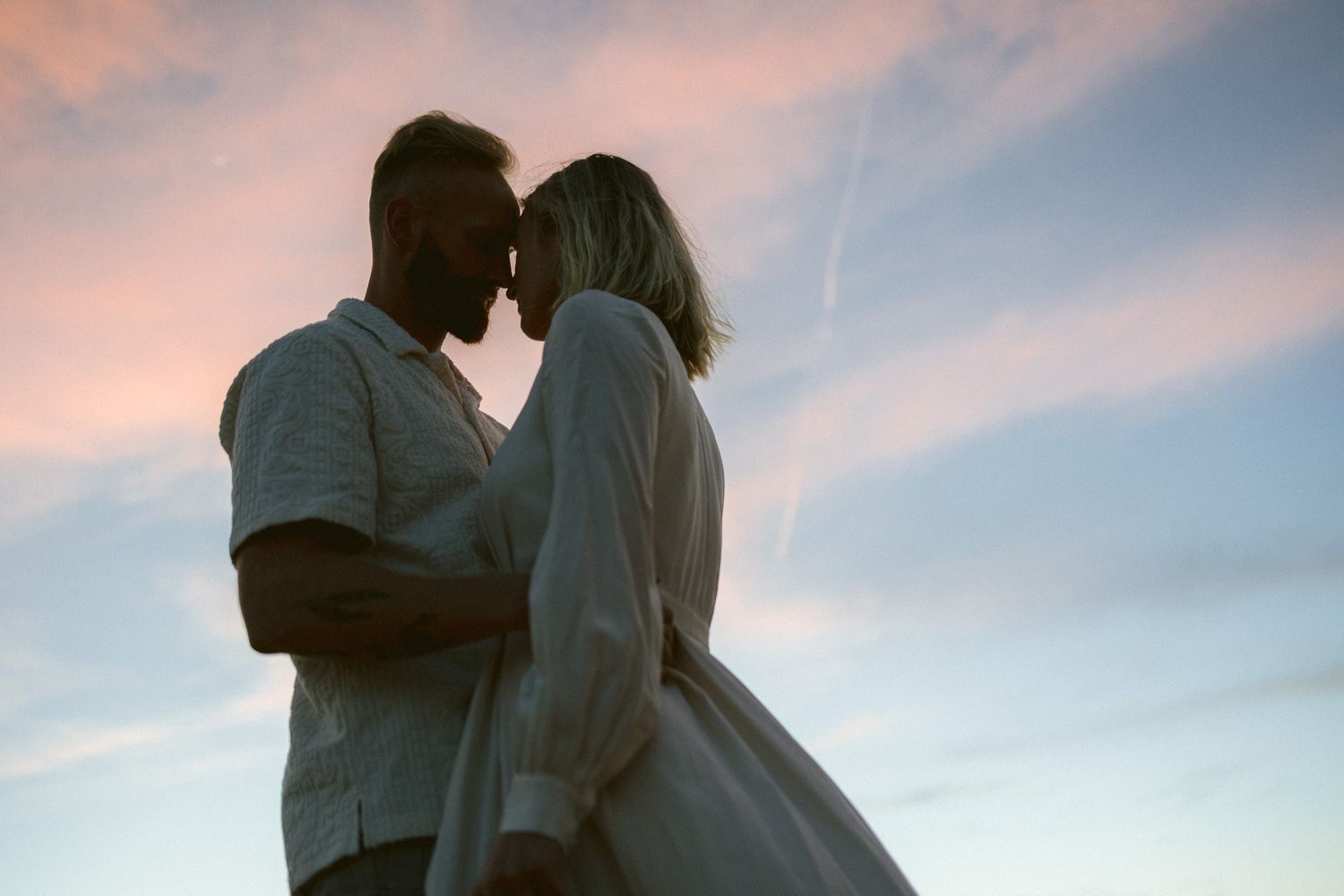 Intimate silhouette of two people in a tender moment during sunset.