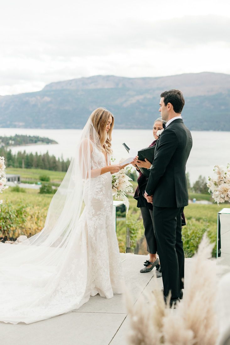 A couple exchanges vows during their mountain-view ceremony with dried floral arrangements.