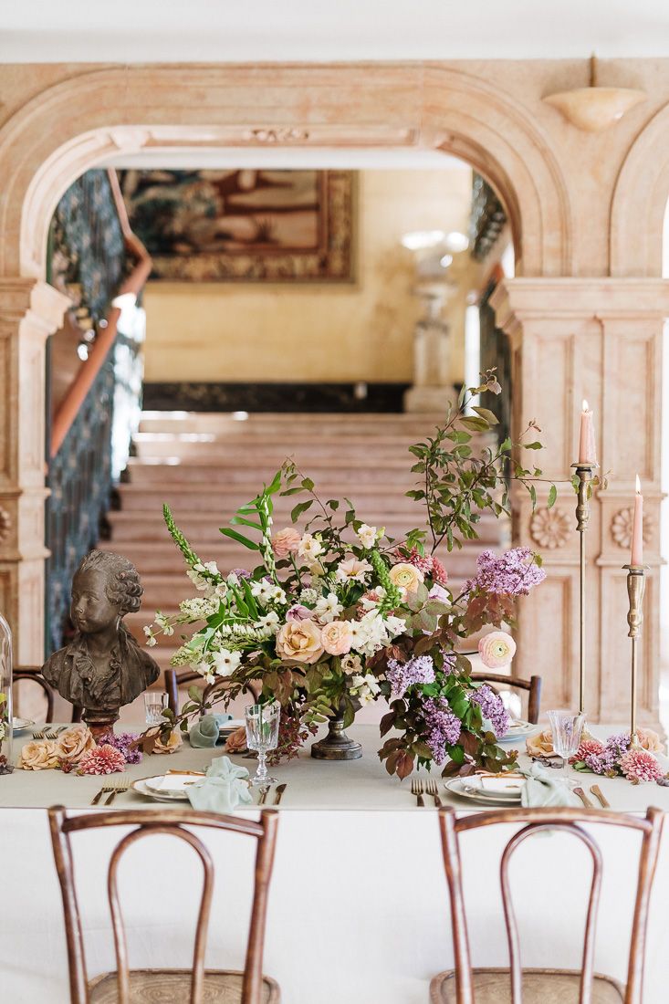 Elegant dining setup with bentwood chairs and floral arrangements framed by classical architectural details.