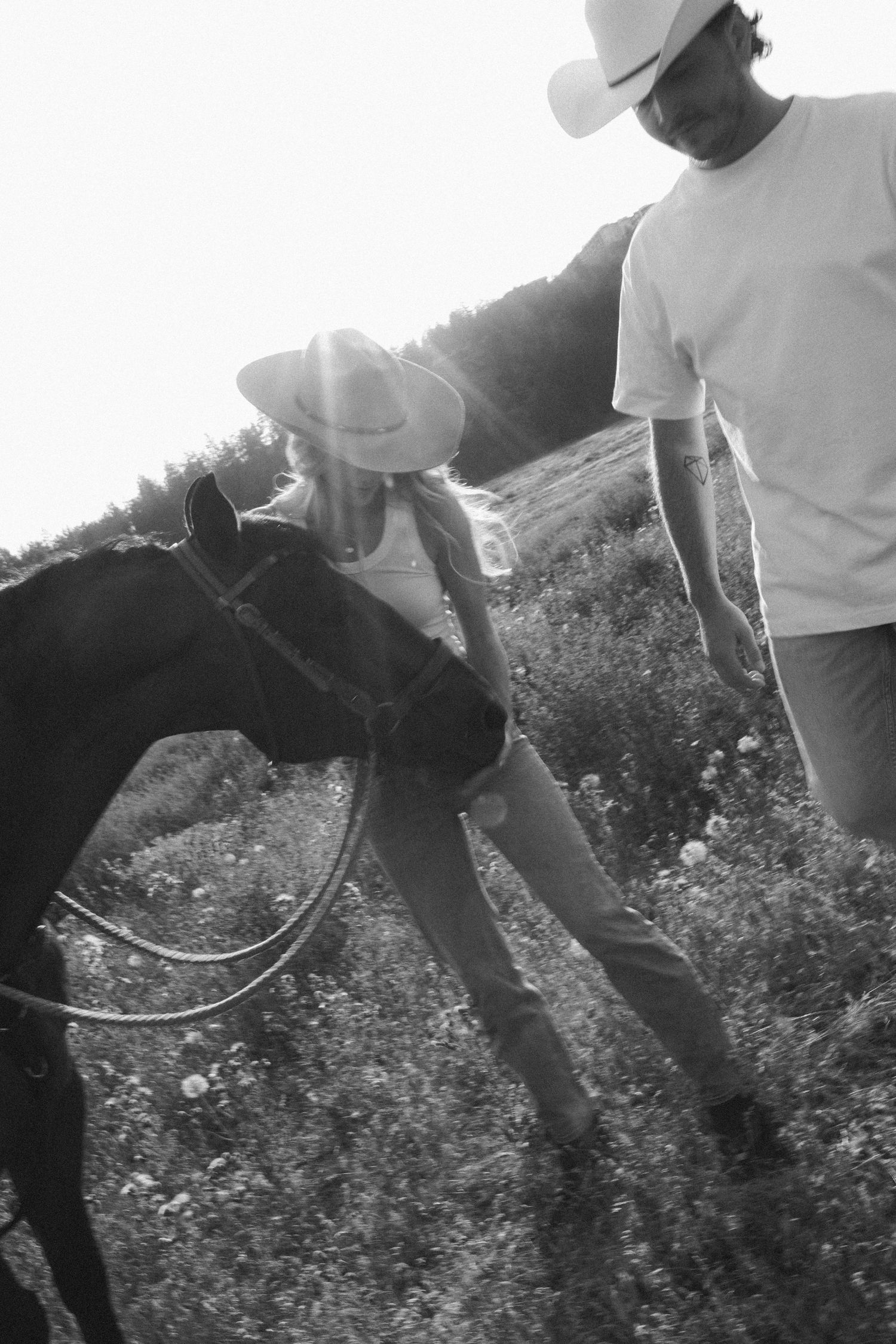 A sequence of black and white photos showing someone playing in tall grass with afternoon sunlight.