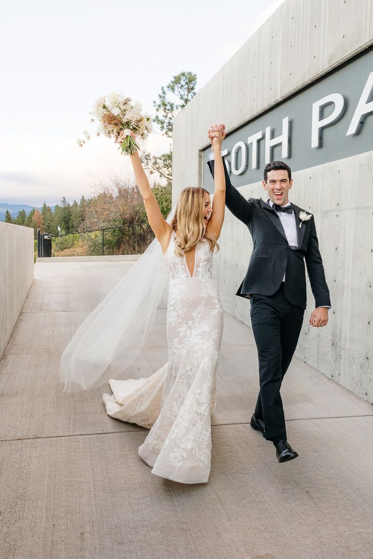 Celebratory moment outside modern building with raised bouquet and joyful expressions.