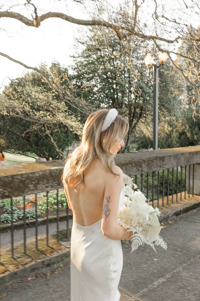 Elegant backless wedding dress shown in outdoor garden setting with natural light.