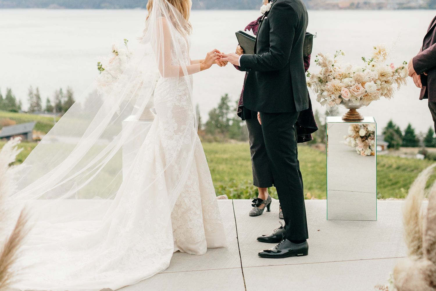 A close-up view of a couple's hands during their wedding ceremony with mountain scenery.
