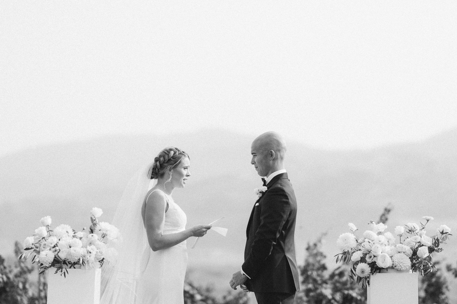 Black and white photo of wedding ceremony with mountain landscape in background.