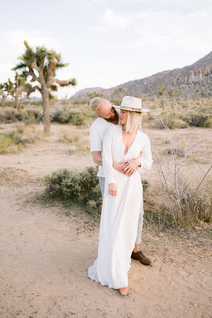 Intimate desert portrait session featuring all-white outfits against scenic mountain backdrop.