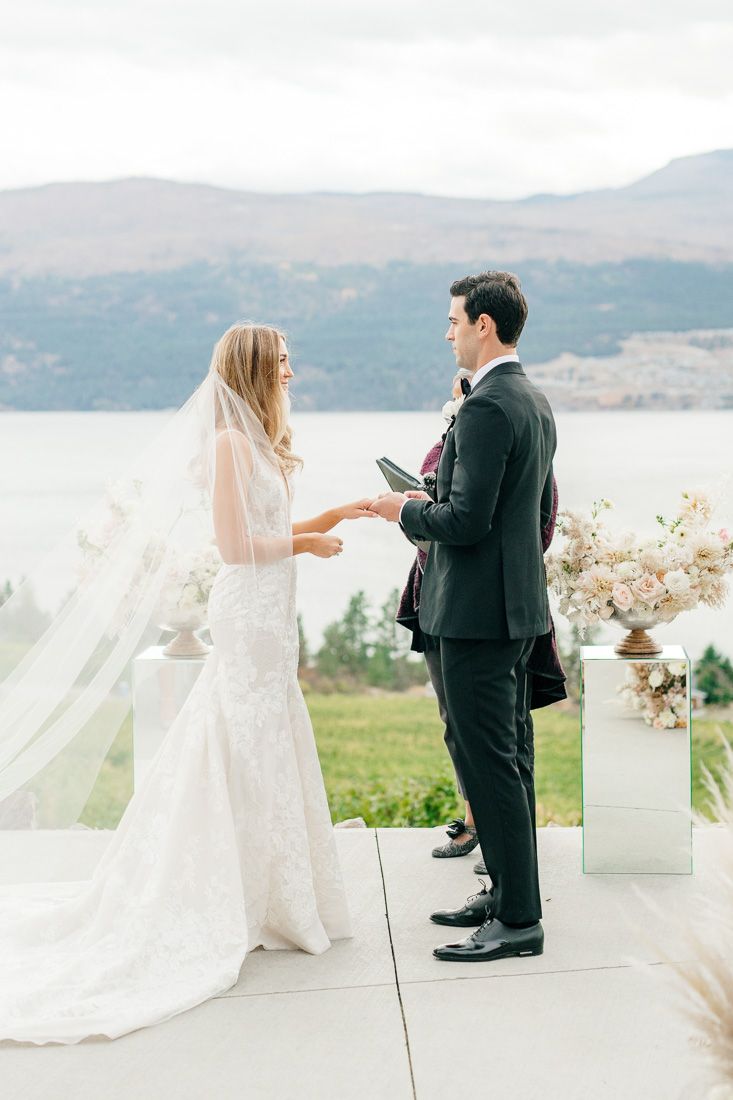 A couple exchanges rings during their ceremony overlooking a scenic mountain lake.