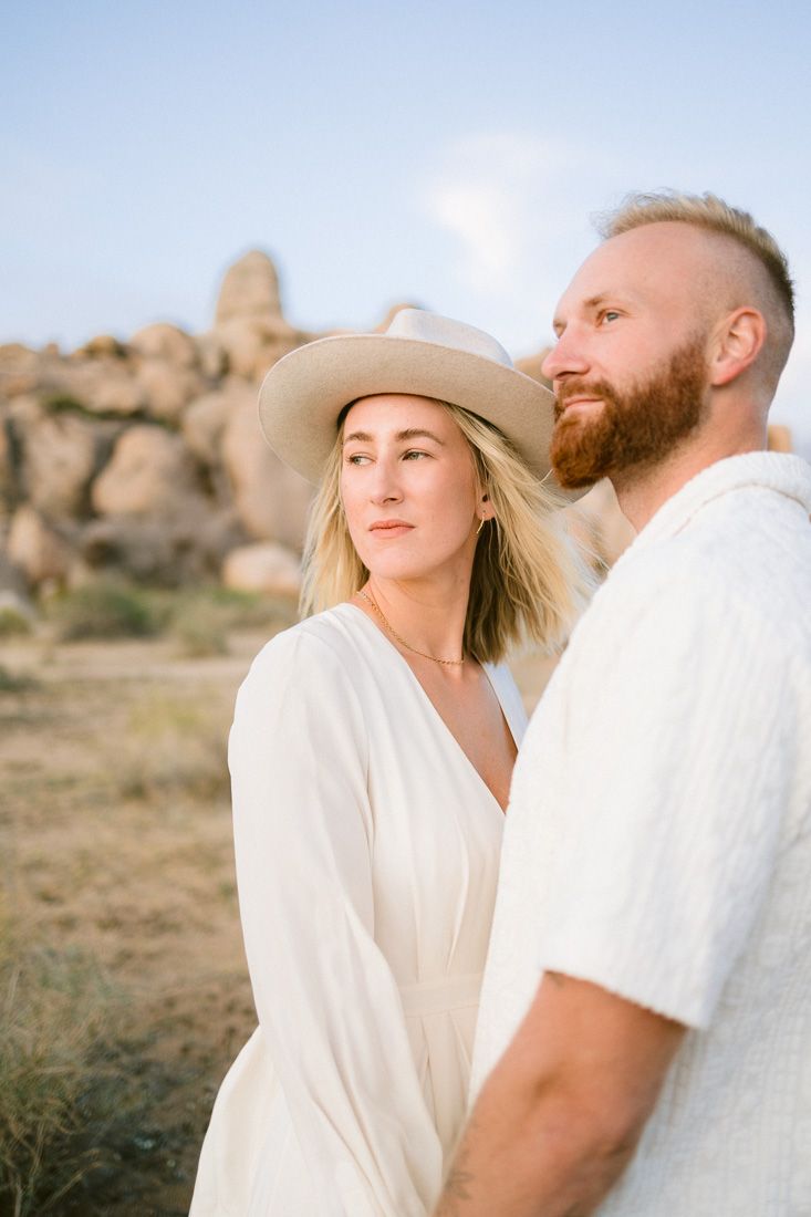 Desert engagement portrait with rocky landscape and Joshua trees in background.