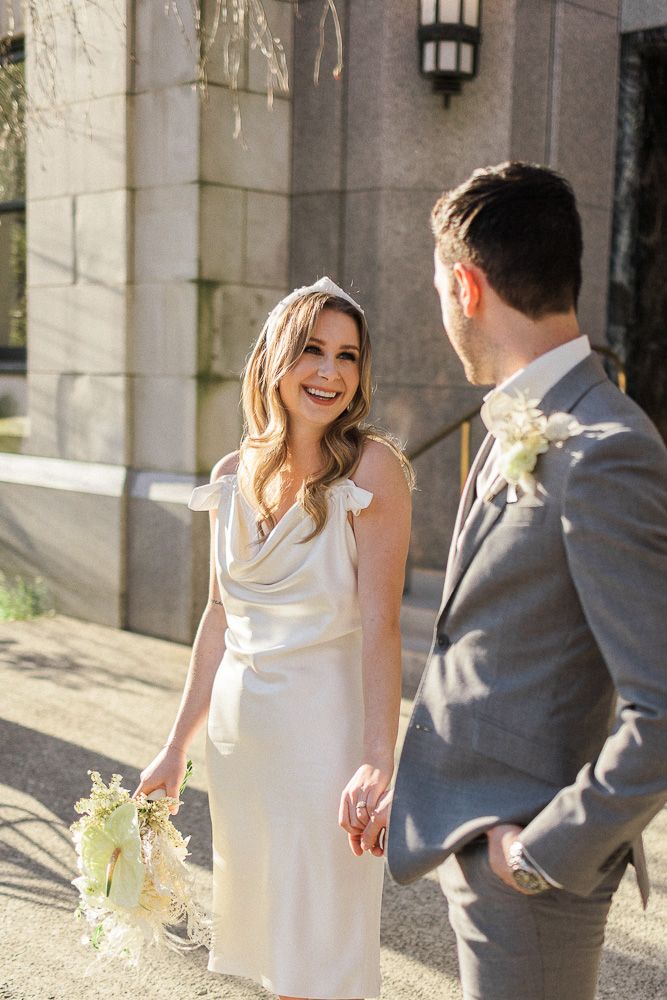 Candid moment between couple in formal attire with natural sunlight.