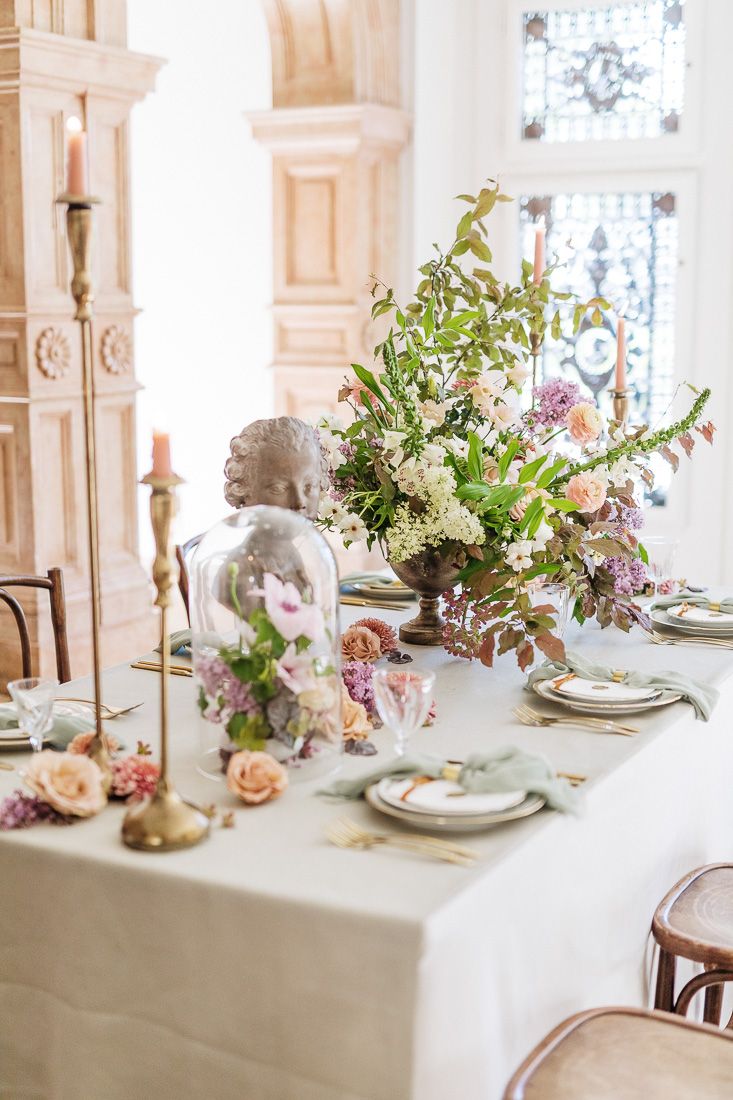 Refined table setting with white linens, glass cloches, and fresh spring floral arrangements.