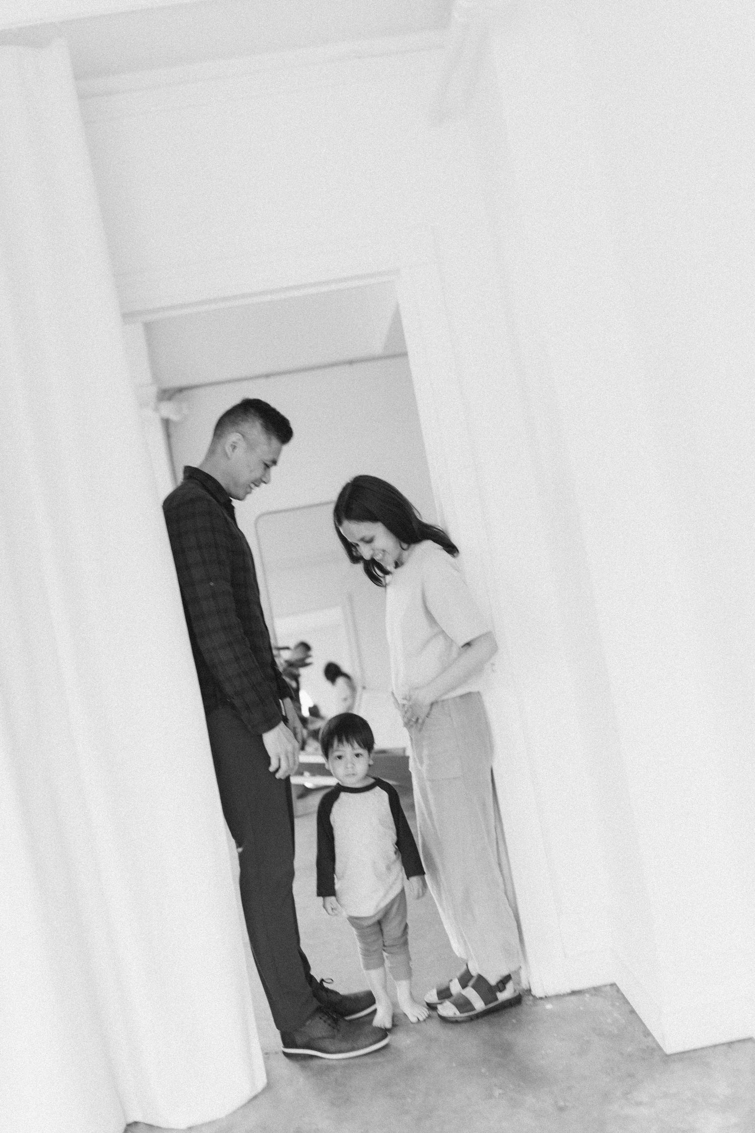 Black and white photo of a family standing together in a minimalist white hallway interior.
