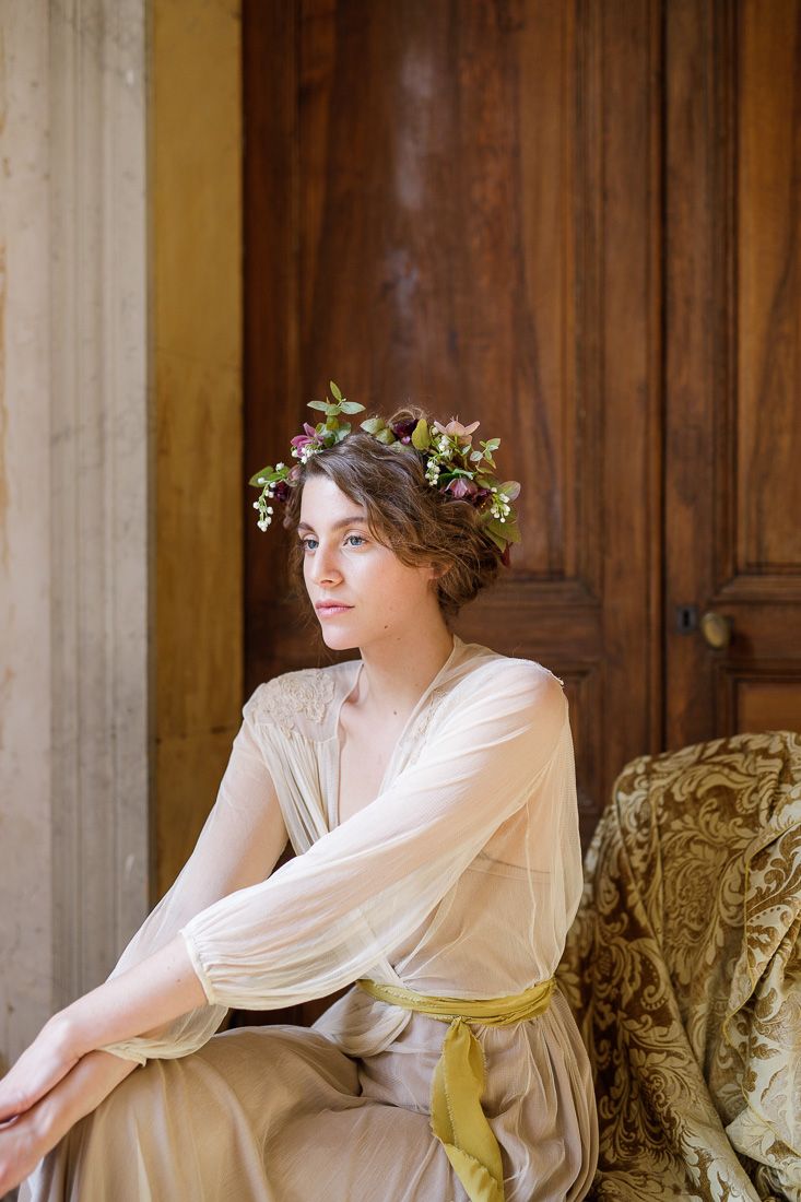 Elegant portrait showing someone in a draped dress with yellow sash seated against ornate furniture.