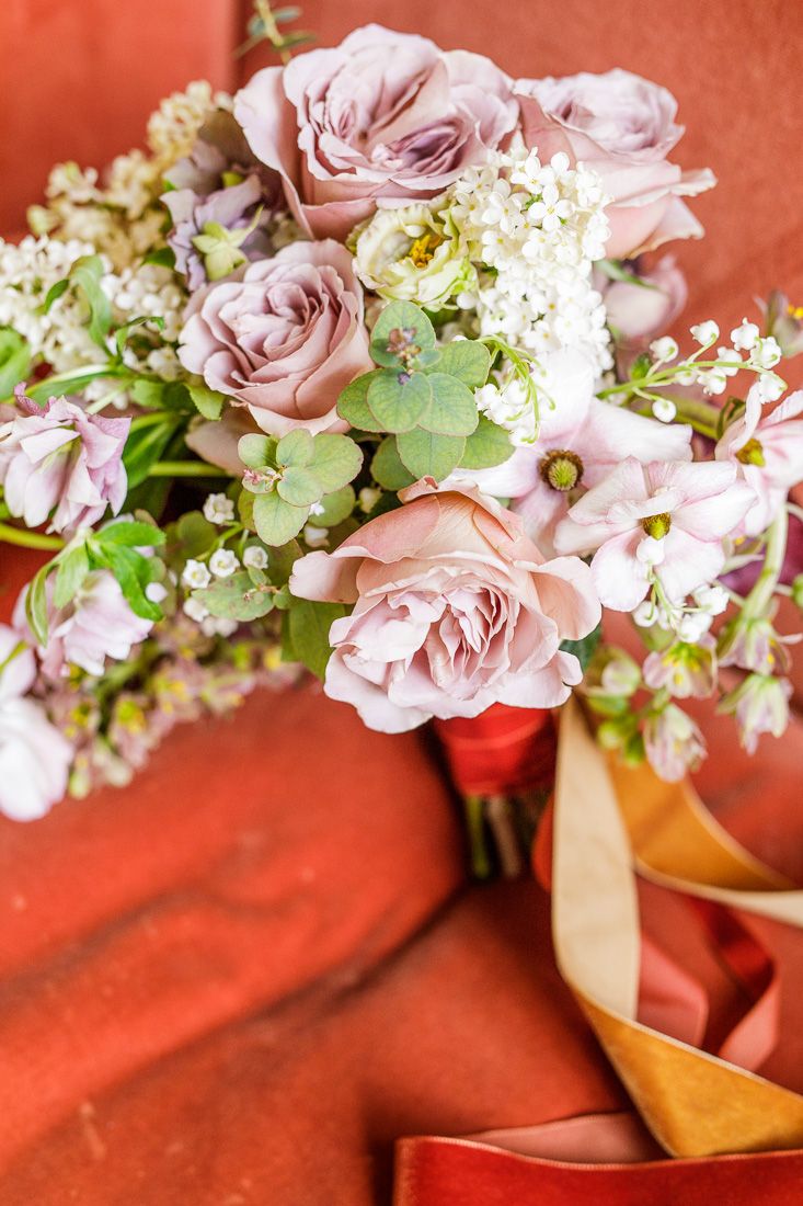 Close-up of romantic bridal bouquet with pink roses and white flowers on coral fabric.