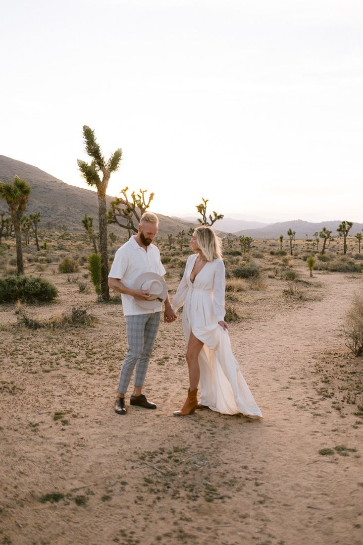 Couple sharing a moment on desert trail surrounded by Joshua trees at dusk.
