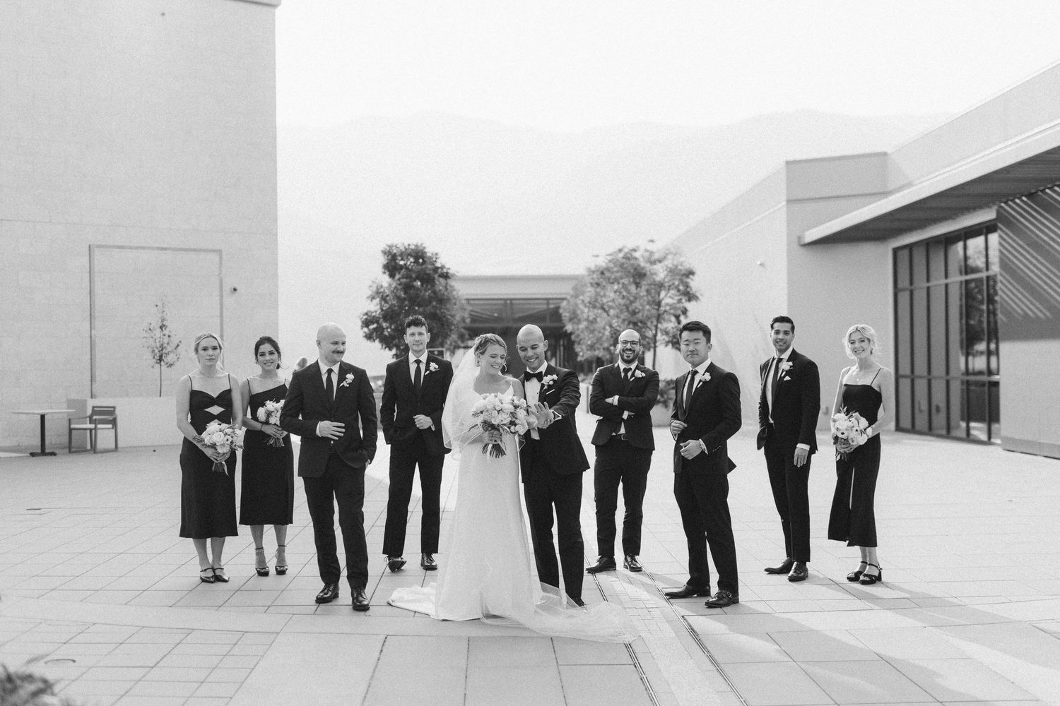 Wedding party lined up in black and white against modern architecture.