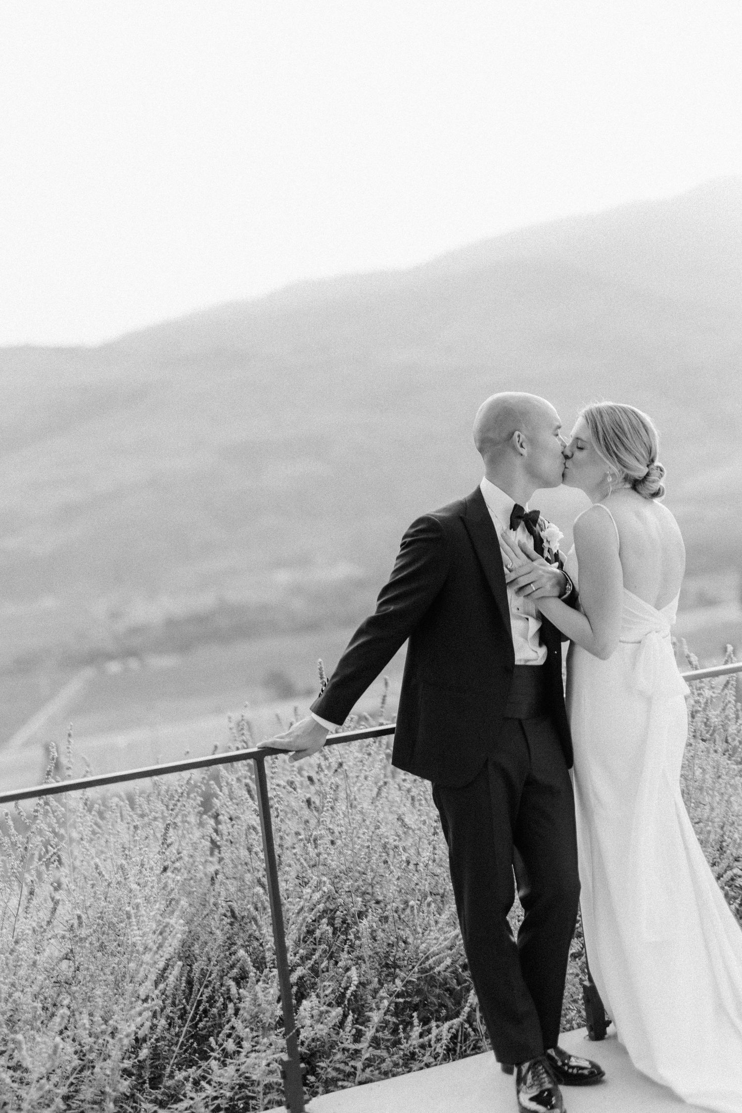 Romantic black and white photo of newlyweds against a scenic mountain backdrop.
