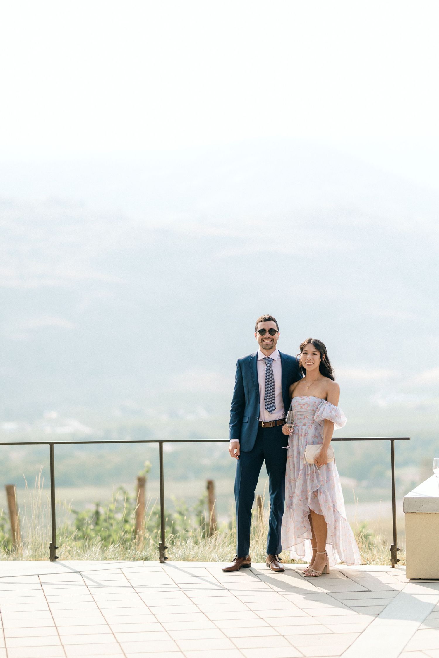 Couple enjoying a romantic moment on a mountain view terrace in formal attire.