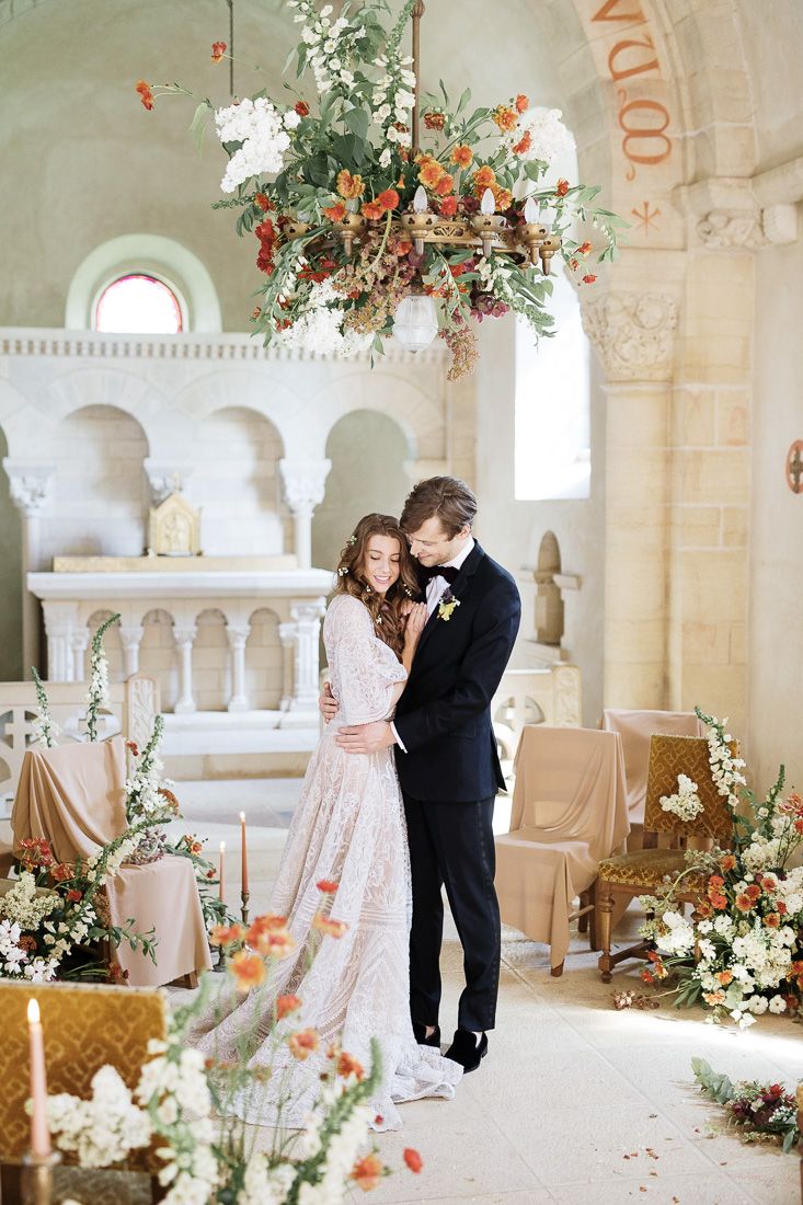 Romantic wedding ceremony setup in a stone chapel with hanging floral installations and soft decor.