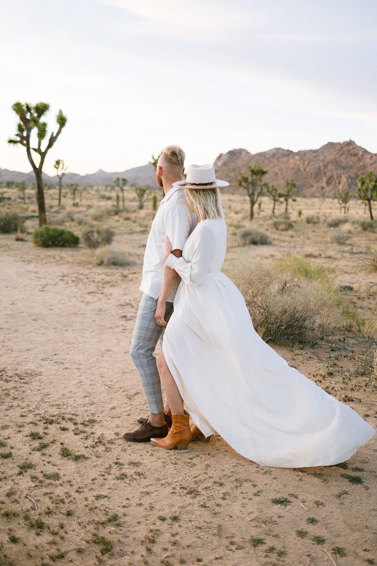 A romantic desert photoshoot with Joshua trees and mountains in the background.